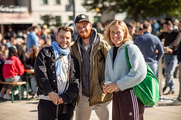 Drei Studierende lächeln entspannt in die Kamera