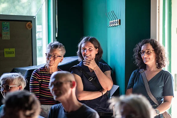 3 Frauen stehen im Hintergrund 