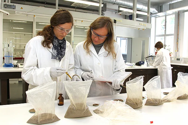 Eine Studentin und eine Mitarbeiterin führen ein Analyseverfahren durch.