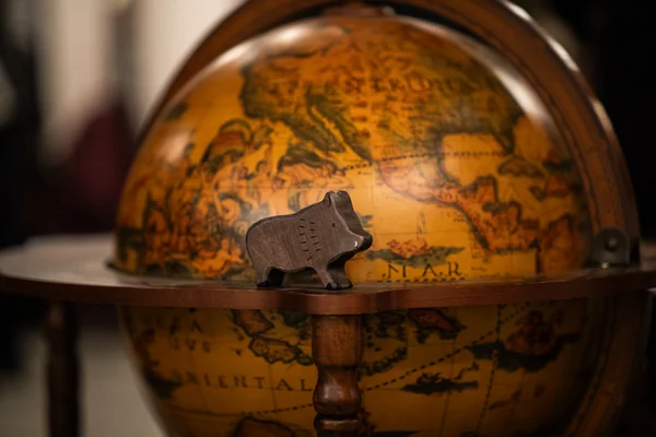 Ein Holzschwein steht vor einem Globus.