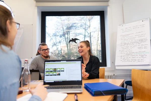 Studierende sitzen gemeinsam an einem Tisch und erarbeiten sich Themen.