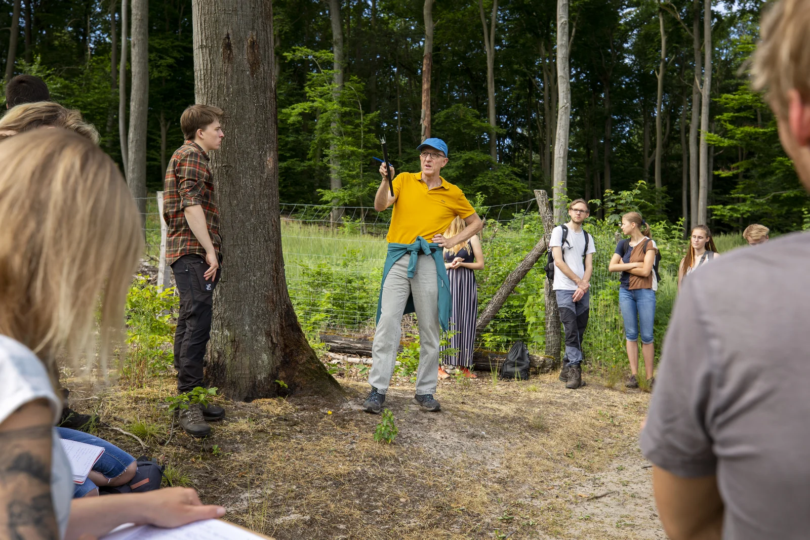 Ein Professor erklärt im Wald und Studiere hören und zu und schreiben mit.