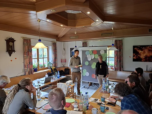 Zwei Personen stellen Ergebnisse der gruppe an einer Pinnwand vor.