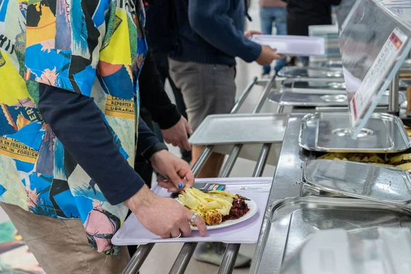 Eine Person stellt gerade einen Teller mit einem Mittagsgericht auf ein Tablett.