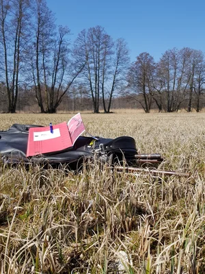 Eine Aktenmappe liegt auf einer schwarzen Tasche. Die befindet sich auf dem Grasboden eines Moores.