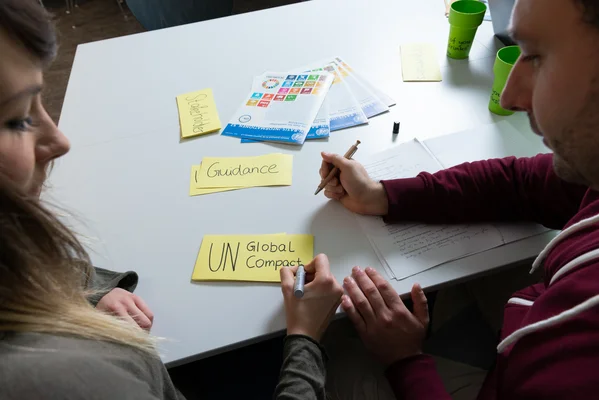 Zwei Studierende schreiben Schlagworte auf Moderationskarten.