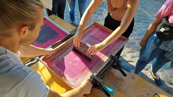 Zwei Personen wenden zusammen die Siebdrucktechnik an.