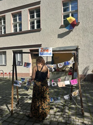 eine Frau steht vor einer leine, an der kleine Broschüren befestigt sind