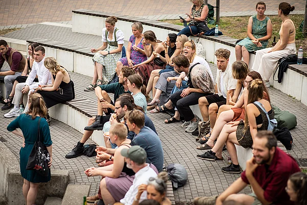 Viele Menschen sitzen feierlich gekleidet auf den Stufen eines Amphitheaters
